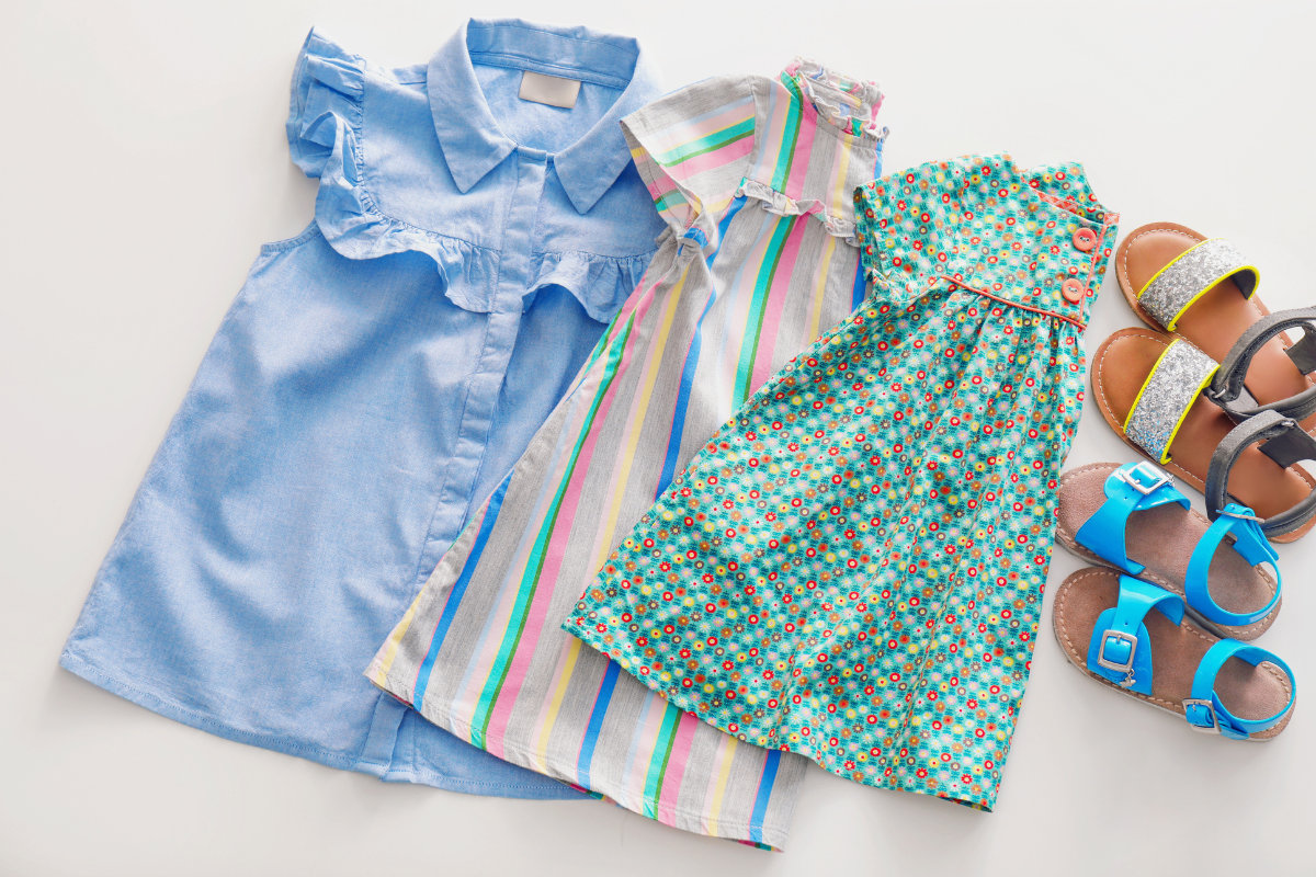Girls’ dresses and sandals arranged for seasonal wardrobe planning before back-to-school shopping.