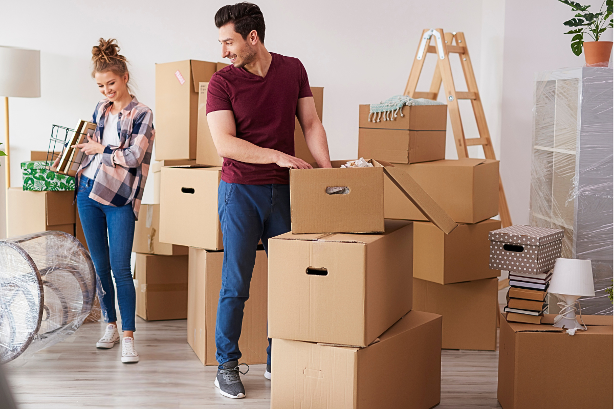 Couple unpacking moving boxes in their new home after thoughtfully editing belongings before the move.