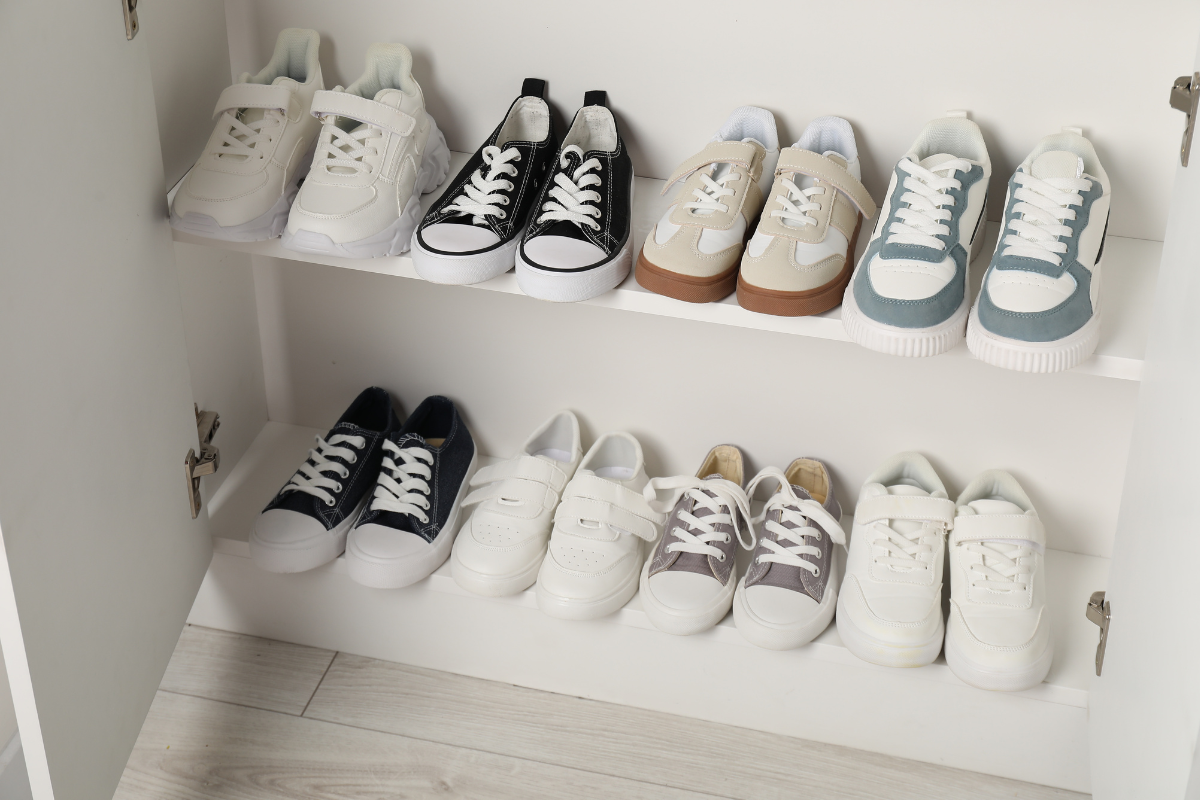 Children’s shoes neatly organized on white closet shelves, showing a simple storage system that supports daily routines.