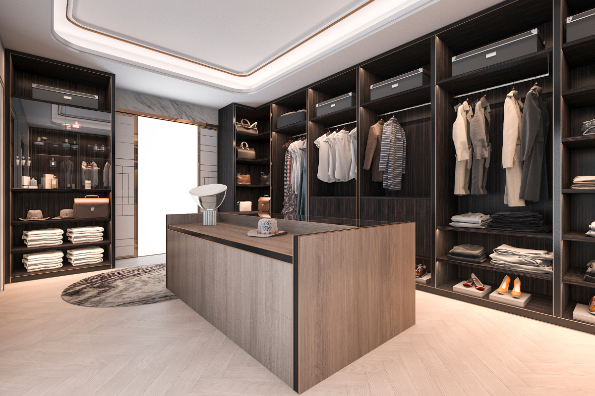 Luxury walk-in wardrobe with clothing, shoes, handbags, and folded items organized in custom dark wood cabinetry.